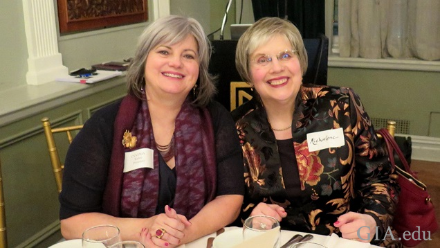 Two woman sit at table for a photo.