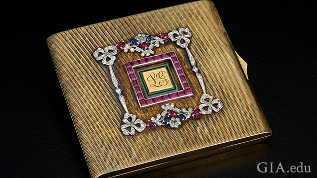 Square, gold compact embellished with garnets and diamonds. Square, gold compact embellished with garnets and diamonds.