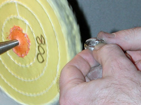 Jeweler polishing a platinum ring at a polishing machine.